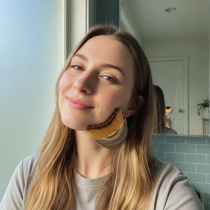 Woman using facial massage tool on jawline in bathroom, natural skincare routine